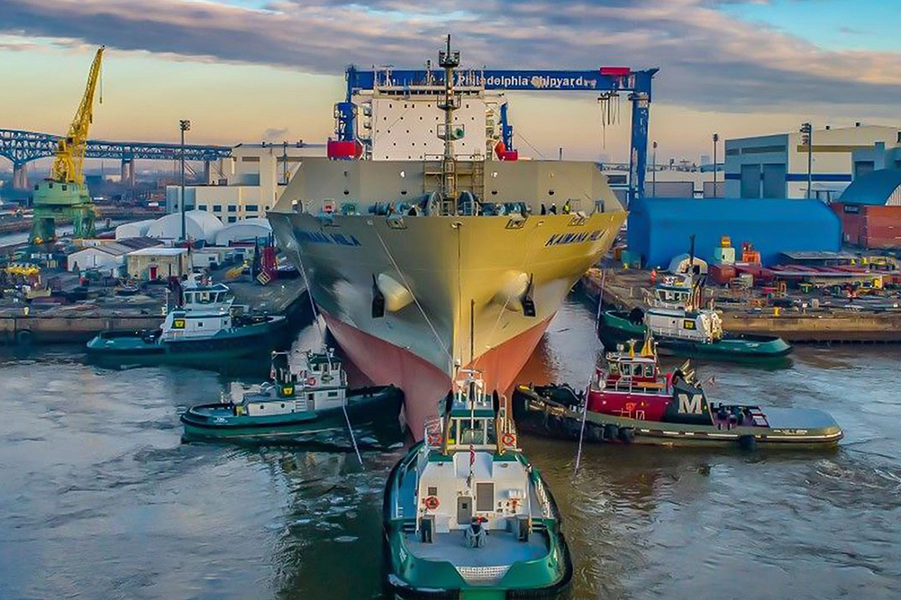 Wide view of a ship docked and tied to tugboats at Hanwha Philly Shipyard