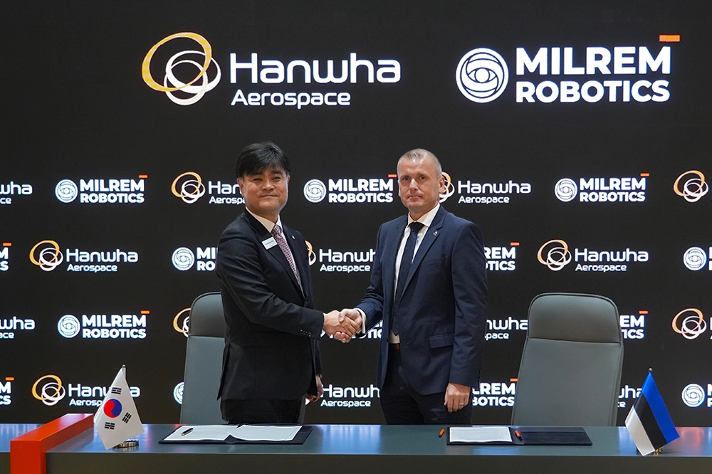 Hanwha Aerospace and Milrem Robotics executives shake hands at the MoU signing ceremony for robotic combat vehicle collaboration.