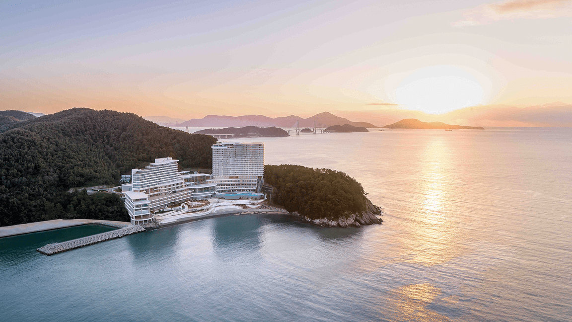 The Hanwha Geoje Belvedere, a Korean luxury resort, is seen at sunset with water in the background.