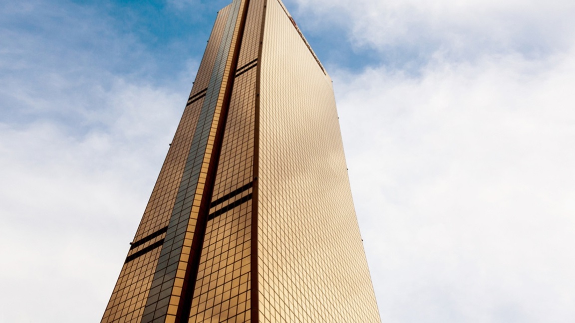 The tall, golden-colored 63 Building in Seoul, Korea, seen from below on a partially cloudy day