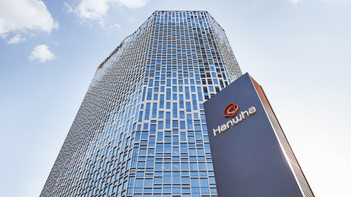 Hanwha’s Seoul headquarters, a skyscraper covered in solar panels, is seen from below on a sunny day. 