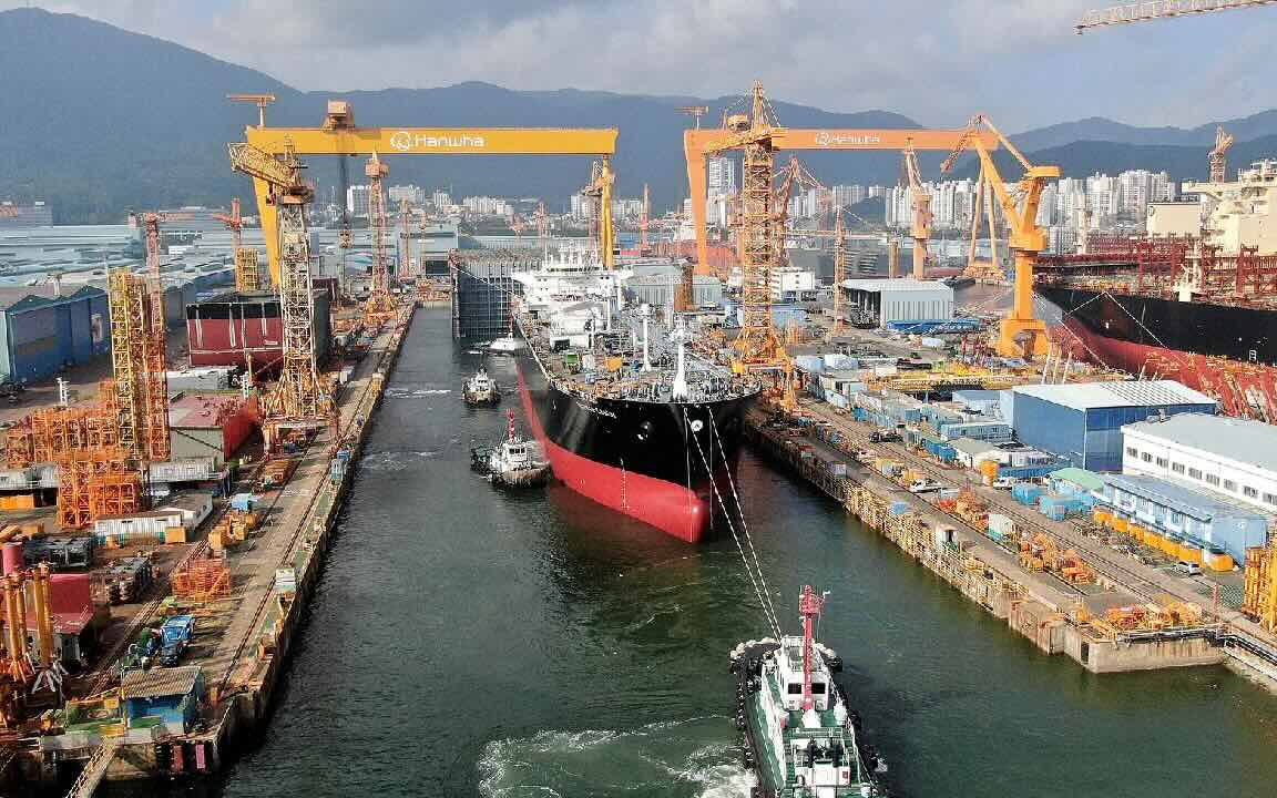 A shipyard with an LPG vessel equipped with a dual fuel engine, surrounded by cranes and industrial equipment 