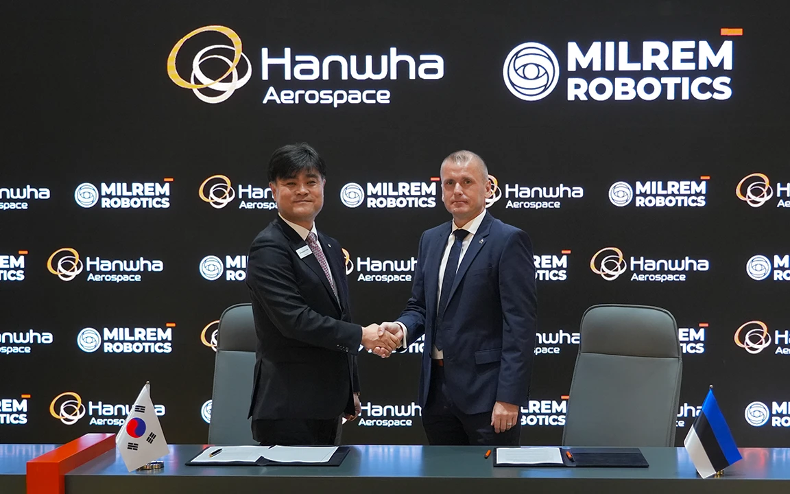 Hanwha Aerospace and Milrem Robotics executives shake hands at the MoU signing ceremony for robotic combat vehicle collaboration.